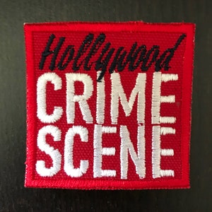 May include: Red fabric patch with white embroidered text that reads "Hollywood Crime Scene" in a bold, stylized font.