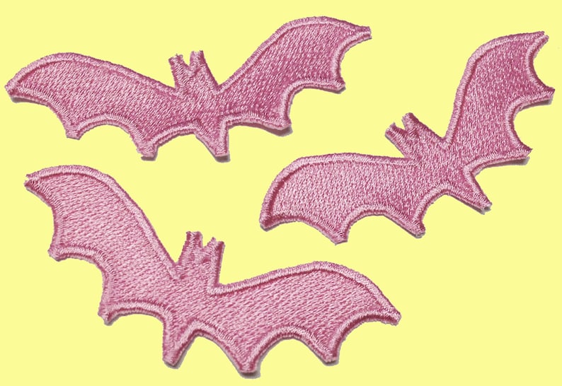 May include: Three pink felt bat appliques. The bats are in various sizes and positions.
