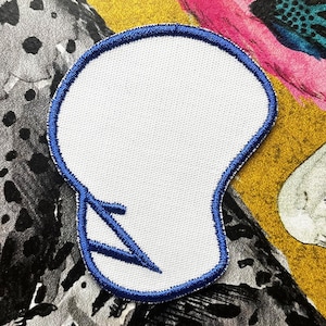 May include: White iron-on patch with a blue outline in the shape of a skull with a lightning bolt design.