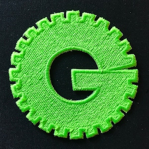 May include: A bright green embroidered patch shaped like a gear with a white letter G in the centre.