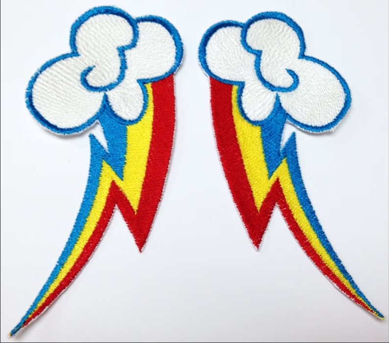 Op de afbeelding: Twee strijkbare patches met een witte wolk met een regenboog en een bliksem. De regenboog is rood, oranje, geel, groen, blauw, indigo en violet. De bliksem is geel.