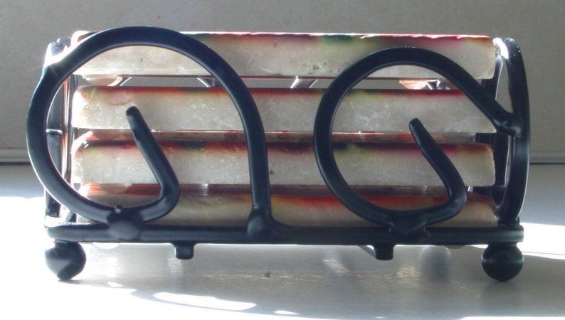 Op de afbeelding: Een zwarte metalen onderzetterhouder met vier witte en rode onderzetters. De houder heeft een uniek ontwerp met twee hoefijzervormige lussen aan elke kant.