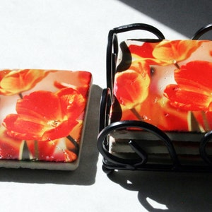 Op de afbeelding: Set van zes oranje en gele bloembedden met een zwarte metalen houder. De onderzetters tonen een close-up afbeelding van oranje en gele tulpen.