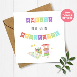 May include: A white card with the text "Amelia Have Fun in Preschool" in colorful letters. The card features a cartoon mouse holding a crayon and a colorful drawing of crayons and a star.