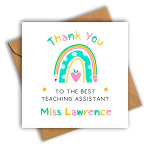 May include: A white card with a rainbow design and the words "Thank You" in teal and pink. The card reads "To the Best Teaching Assistant Miss Lawrence" in a playful font. The card is on a brown envelope.