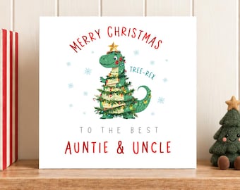 May include: A square greeting card with a white background featuring a green dinosaur wrapped in Christmas lights and a gold star on its head. The text reads Merry Christmas Tree-Rex to the best Auntie & Uncle, surrounded by blue snowflakes.