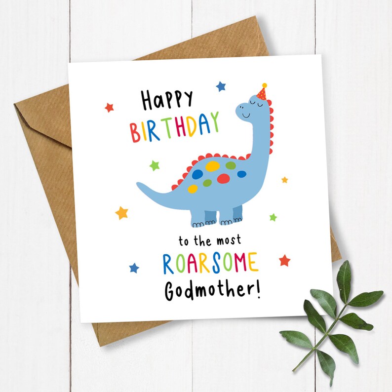 Op de afbeelding: Een vierkante witte wenskaart met een blauwe cartoon-dinosaurus met een feesthoedje, omringd door kleurrijke sterren. De tekst luidt: Happy Birthday to the most ROARSOME Godmother! De kaart ligt op een bruine envelop.