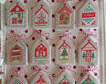 May include: Twelve handmade Christmas ornaments in the shape of houses with various red, green, and white designs. The ornaments are displayed on a white background with red polka dots.