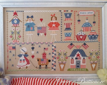 May include: A cross-stitch sampler featuring a patriotic theme with red, white, and blue colors. The sampler includes images of a birdhouse, a girl holding a flag, a house, cupcakes, and other patriotic symbols. The text "PATRIOTIC CUPCAKES" and "WELCOME" are included in the sampler.