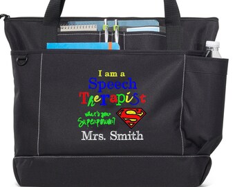 May include: Black tote bag with white stitching and multiple pockets. The bag features the text "I am a Speech Therapist, what's your Superpower?" with a Superman logo and "Mrs. Smith" embroidered in colorful thread. The text "Scooter Trash Custom Embroidery" is above the bag.