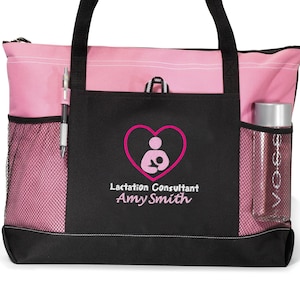 May include: A black and pink tote bag with a zippered top and a mesh pocket on each side. The bag has a pink heart with a breastfeeding mother and child graphic and the text "Lactation Consultant Amy Smith".