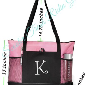 May include: A pink and black tote bag with a mesh pocket and a zippered closure. The bag has a large letter "K" embroidered on the front. The bag measures 19 inches wide, 14.75 inches tall, and 4 inches deep.