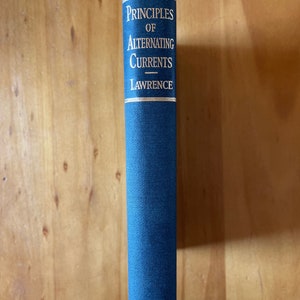 May include: A blue hardcover book titled "Principles of Alternating Currents" by Lawrence. The book is published by McGraw-Hill Book Company.