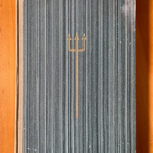 May include: A dark blue book with a gold trident symbol on the front cover.