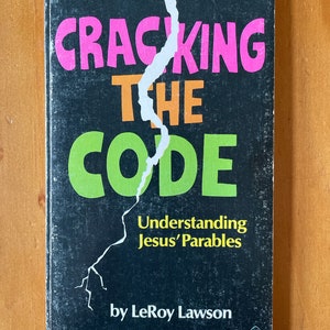 May include: A black book with a torn cover. The title is "Cracking the Code" in pink, orange, and green letters. The subtitle is "Understanding Jesus' Parables" in white letters. The author is "by LeRoy Lawson" in white letters.