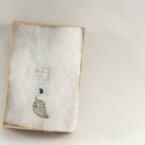 May include: Silver ear cuff with a dangling leaf charm and a blue iridescent bead.