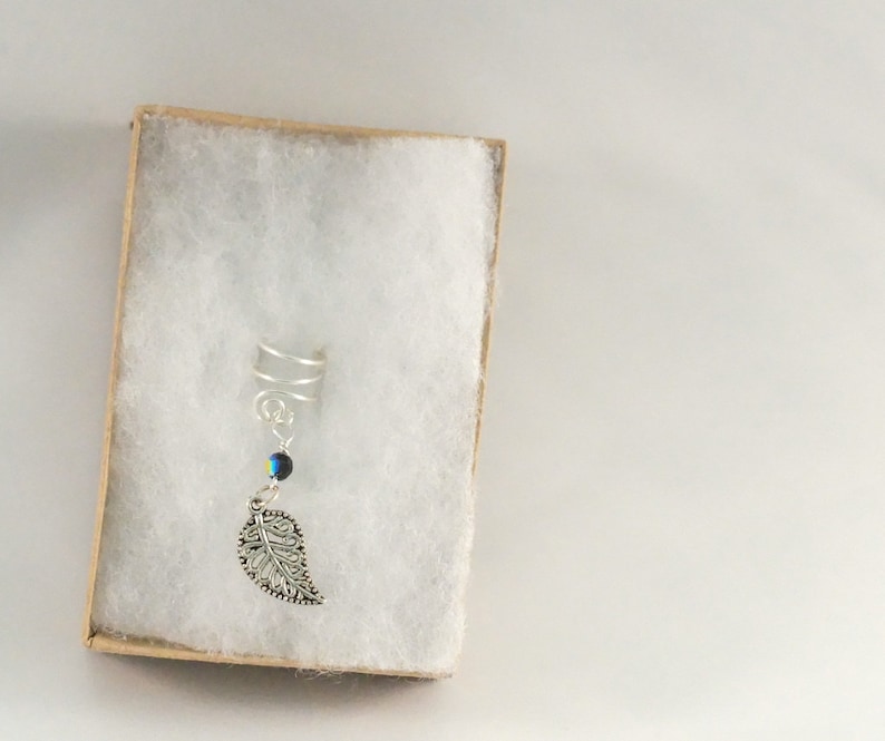 May include: Silver ear cuff with a dangling leaf charm and a blue iridescent bead.