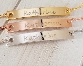 May include: Three gold, rose gold, and silver bar bracelets with the name "Katherine" engraved on each.