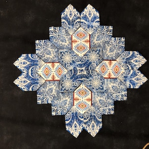 May include: A decorative, geometric design composed of blue and white patterned tiles. The tiles feature a paisley and snowflake-like pattern, with red and yellow geometric accents in the center.