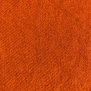 May include: Close-up of a textured, orange fabric. The material has a woven appearance, with visible threads creating a slightly rough surface. The color is a vibrant, warm orange, filling the frame.