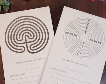 May include: Two printable labyrinth worksheets with a black and white design. Each worksheet has a space to write "My intention today is to FOCUS on:" and "Information Received:" with lines for writing. The bottom of each worksheet has the website address "www.focuslabyrinth.com".