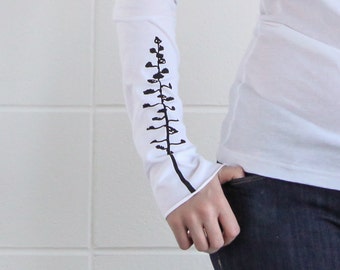 Könnte beinhalten: Weißes Langarmshirt mit einer schwarzen Grafik einer stilisierten Pflanze auf dem Ärmel.