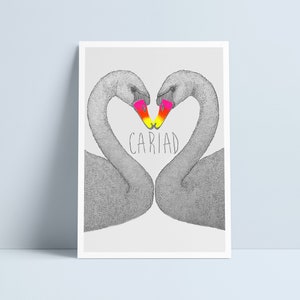 May include: A black and white illustration of two swans forming a heart shape with their necks. Their beaks are coloured in a gradient of pink, yellow, and orange. The word "CARIAD" is written in black below the swans.