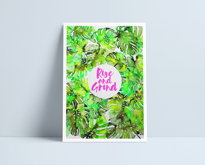 May include: A motivational poster with a watercolor illustration of green tropical leaves. The text "Rise and Grind" is written in pink inside a white circle.