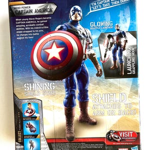 Op de afbeelding: Captain America actionfiguur met een gloeiende grijphaakwerper en een rood-wit-blauw schild. De verpakking toont het iconische rood-wit-blauwe kostuum van het personage en de tekst "Ik ben Captain America!" "Laten we ze verslaan!"