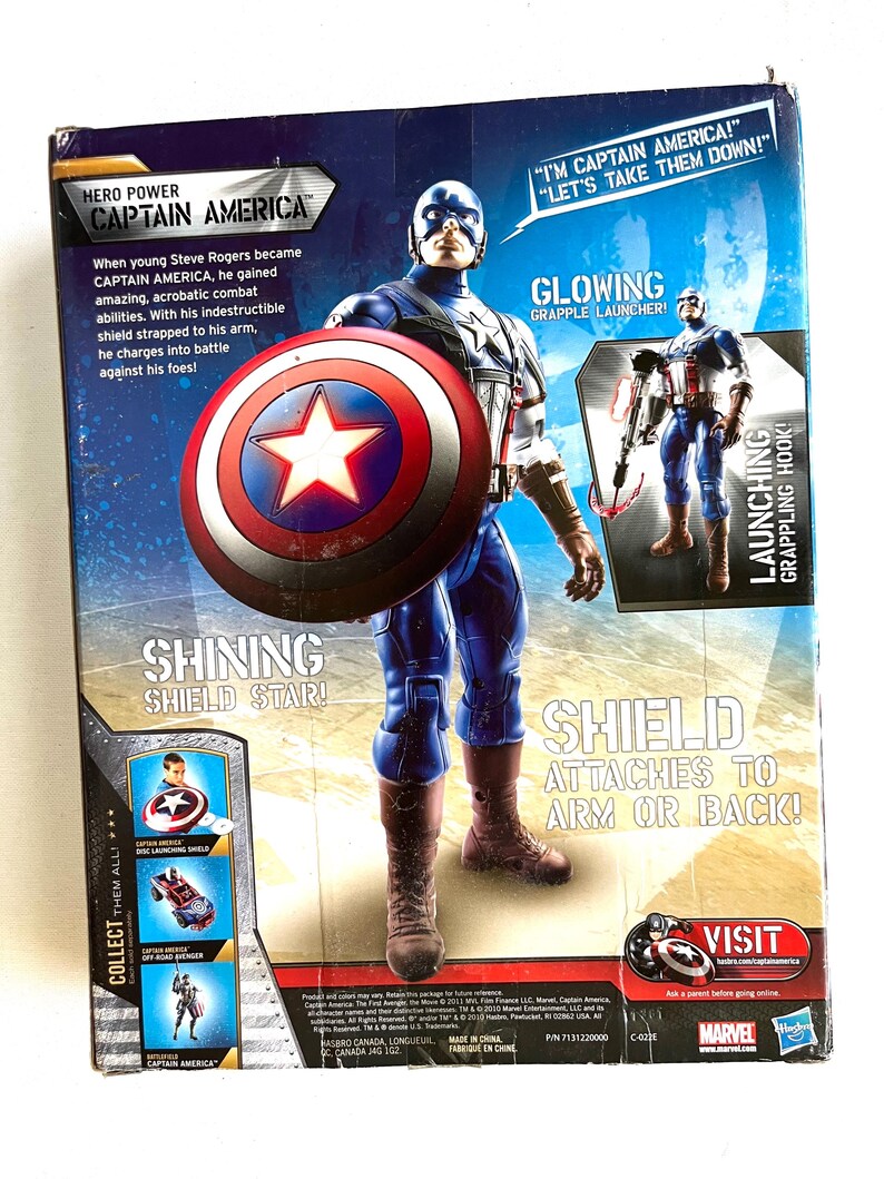 Op de afbeelding: Captain America actionfiguur met een gloeiende grijphaakwerper en een rood-wit-blauw schild. De verpakking toont het iconische rood-wit-blauwe kostuum van het personage en de tekst "Ik ben Captain America!" "Laten we ze verslaan!"