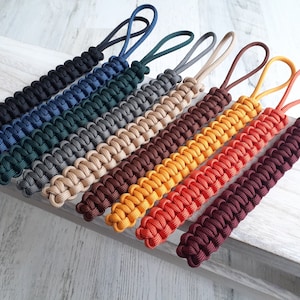 May include: A set of ten colorful paracord keychains, each with a different color and pattern. The keychains are made of durable paracord and are perfect for adding a touch of personality to your keys.