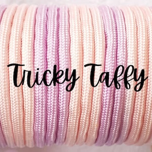 May include: Close-up of a pink and peach paracord, with the text "Tricky Taffy" printed on it.