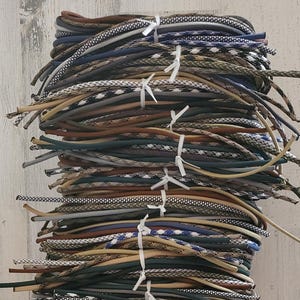 May include: A large stack of colorful paracord, a type of strong nylon cord, in various patterns and colors. The paracord is bundled together and tied with white string.
