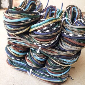 May include: A stack of colorful paracord, with various patterns and colors, including blue, green, brown, and white.
