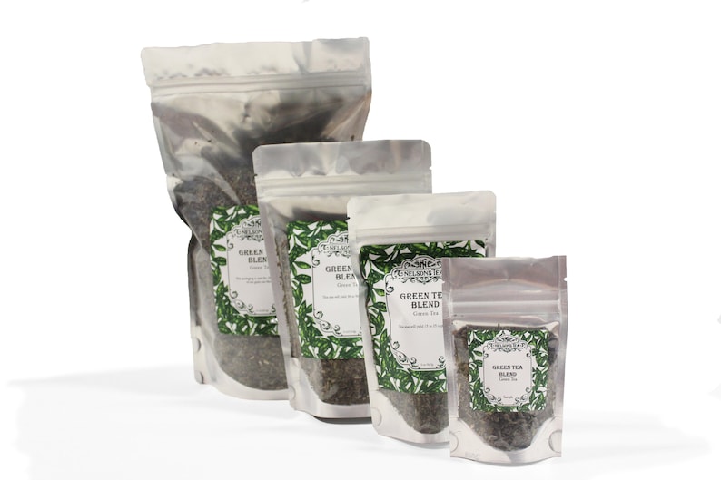 May include: Four silver foil pouches of green tea blend, in various sizes, with a white label featuring a green tea leaf design and the text "Green Tea Blend" in black.