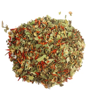 May include: A close-up of a blend of dried herbs and spices, including green leaves, red flower petals, and small brown seeds. The mixture is arranged in a loose pile on a white background.