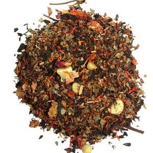 May include: A close-up of a blend of loose leaf tea with dried fruit pieces, herbs, and spices. The tea blend is a mix of brown, orange, and red colors.