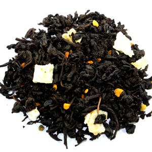 May include: A close-up of a black tea blend with white and yellow pieces. The tea is loose leaf and appears to be a blend of black tea, white tea, and dried fruit.