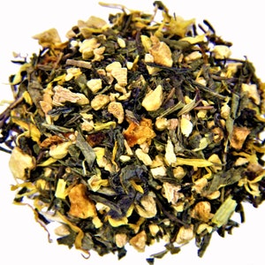 May include: A close-up of a blend of green tea, ginger, and orange peel. The tea is a mix of green leaves, small pieces of ginger, and orange peel.