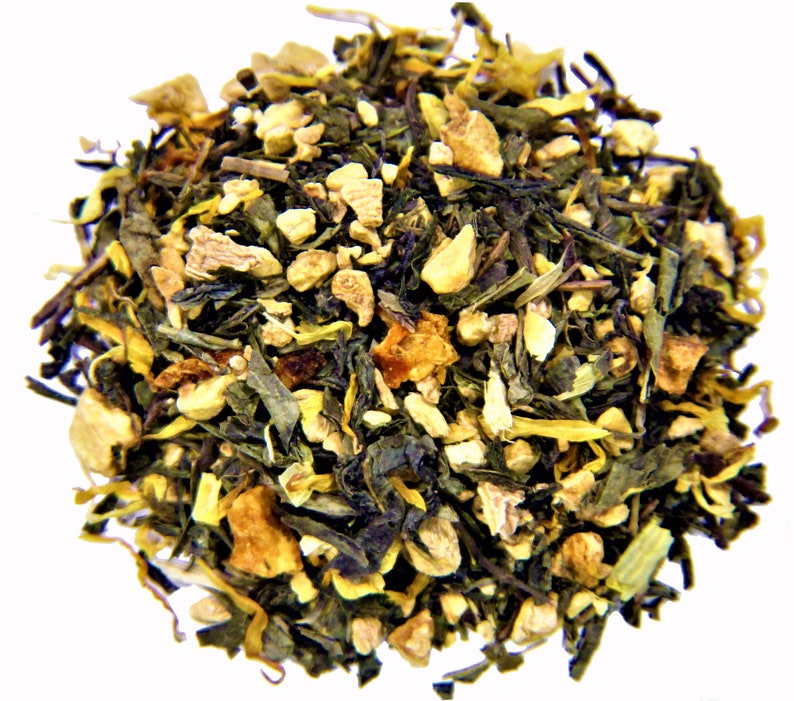 May include: A close-up of a blend of green tea, ginger, and orange peel. The tea is a mix of green leaves, small pieces of ginger, and orange peel.