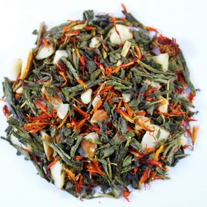 May include: A blend of green tea, almonds, and saffron. The tea is a mix of green leaves, orange-red saffron threads, and white almond pieces.