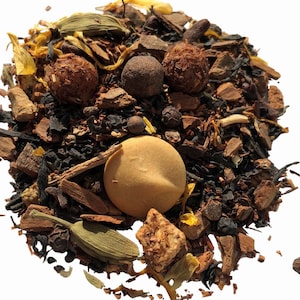 May include: A close-up of a loose leaf tea blend with black tea, cinnamon sticks, dried fruit, and spices. The tea blend is a mix of brown, orange, and green colors.
