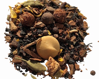 May include: A close-up of a loose leaf tea blend with black tea, cinnamon sticks, dried fruit, and spices. The tea blend is a mix of brown, orange, and green colors.