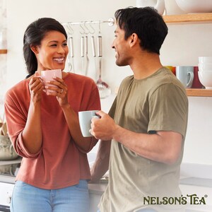 May include: A couple enjoying a cup of tea together in a kitchen. The woman is wearing a pink shirt and blue jeans, while the man is wearing a green shirt. They are both smiling and looking at each other. The text "NELSON'S TEA" is visible in the bottom right corner of the image.