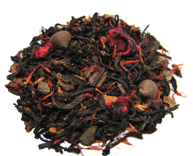 May include: A close-up of a blend of black tea leaves, dried fruit pieces, and chocolate chips. The tea blend is a mix of black tea, dried cranberries, and chocolate chips.