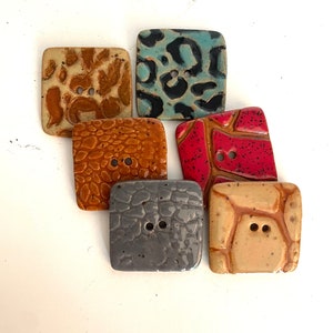 May include: Six square ceramic buttons in various colors and patterns. The buttons include a teal leopard print, red mosaic, and textured brown and tan designs. Each button has two holes for sewing.