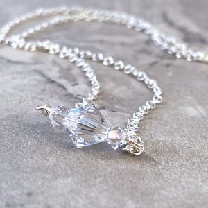 Puede incluir: Un collar de cadena de plata con un colgante de cristal transparente.