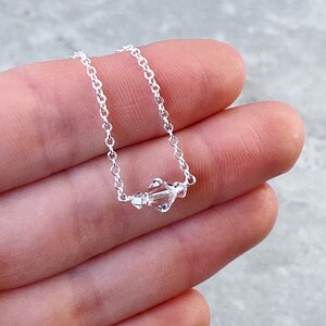 Puede incluir: Un delicado collar de cadena de plata con tres cuentas de cristal transparentes.