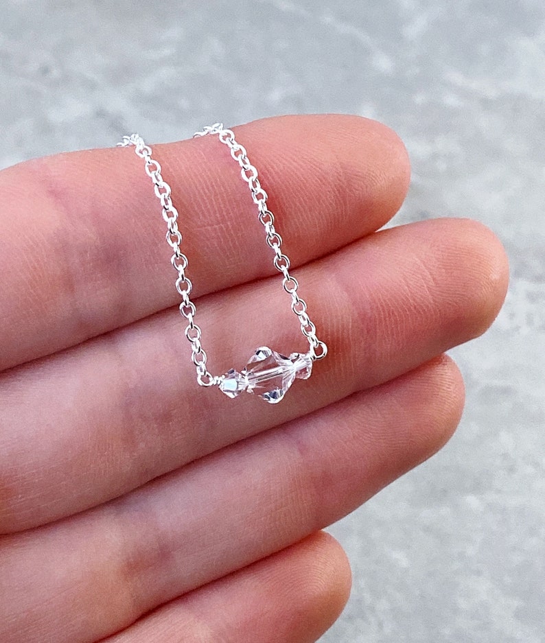 Puede incluir: Un delicado collar de cadena de plata con tres cuentas de cristal transparentes.