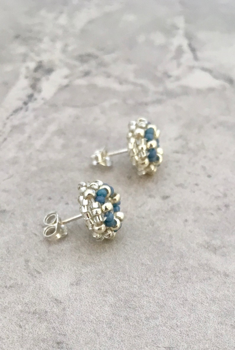 Puede incluir: Un par de pendientes de bot&oacute;n de plata con detalles de cuentas azules. Los pendientes son peque&ntilde;os y delicados, y ser&iacute;an un gran regalo para un amigo o un ser querido.